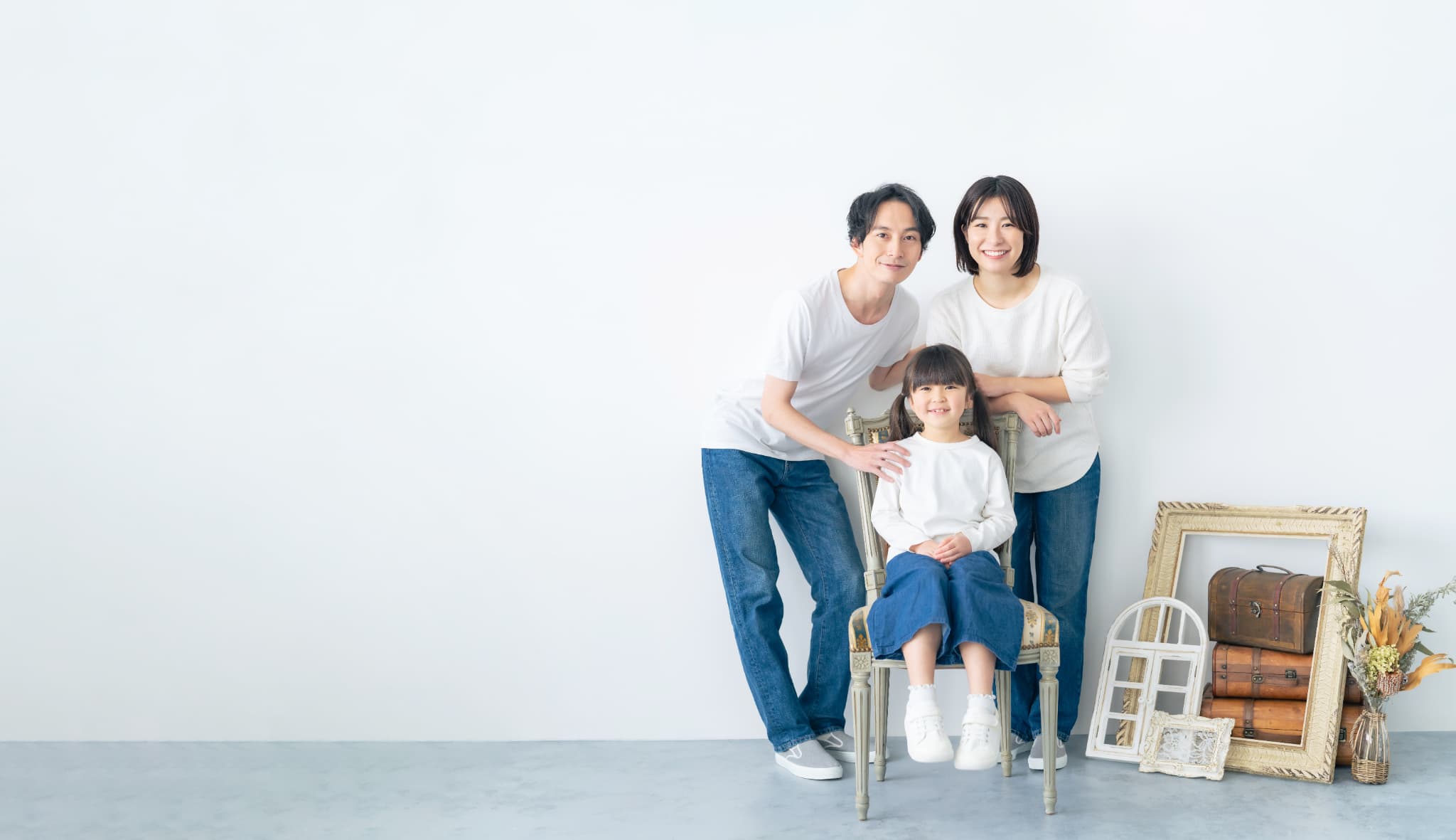 3人家族が集まっています。右側には植物や額縁などの飾り物が置かれています。