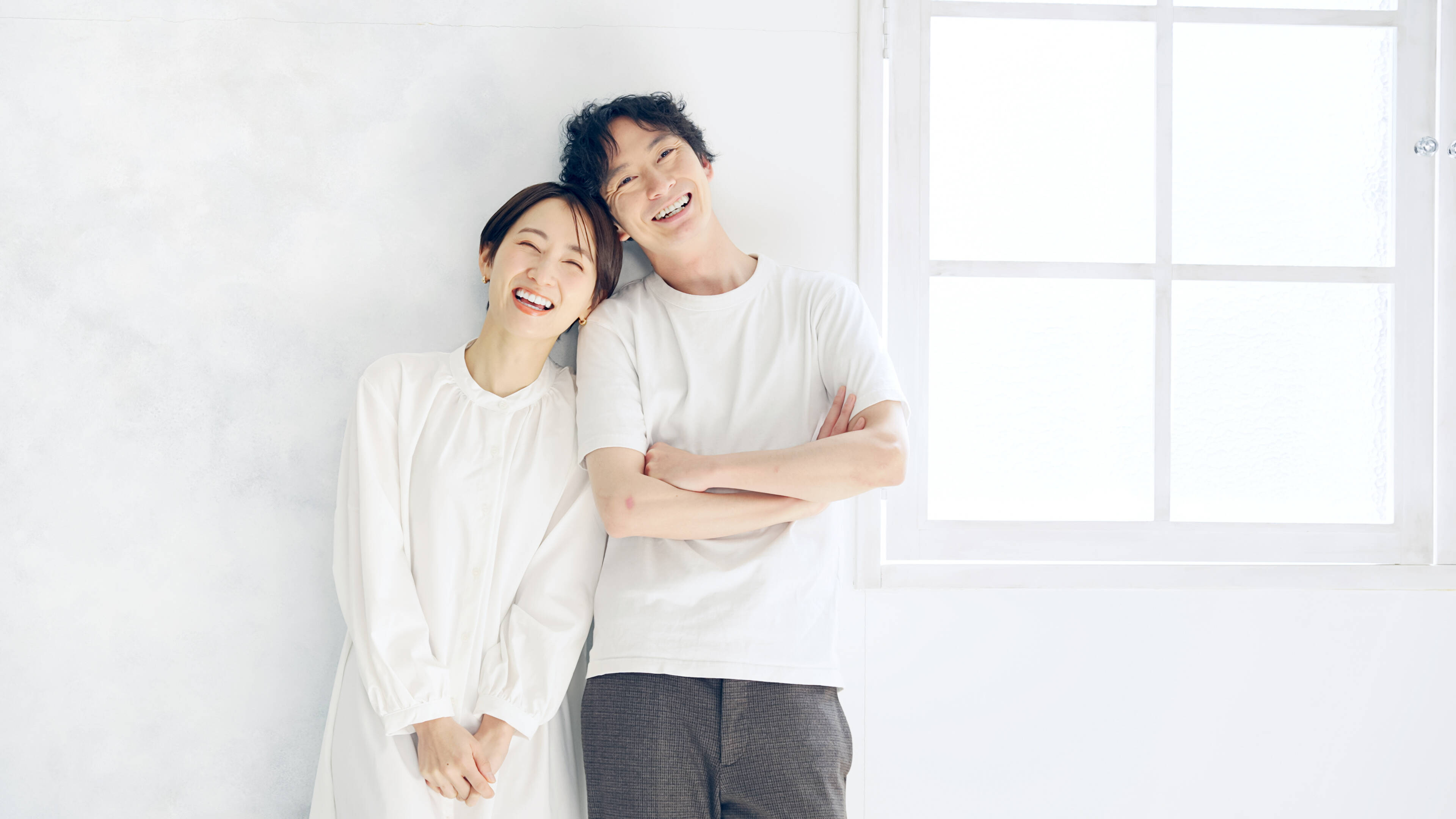 ココニフォトスタジオを運営している夫婦2人が、肩を寄せながら笑顔でこちらを見つめています。