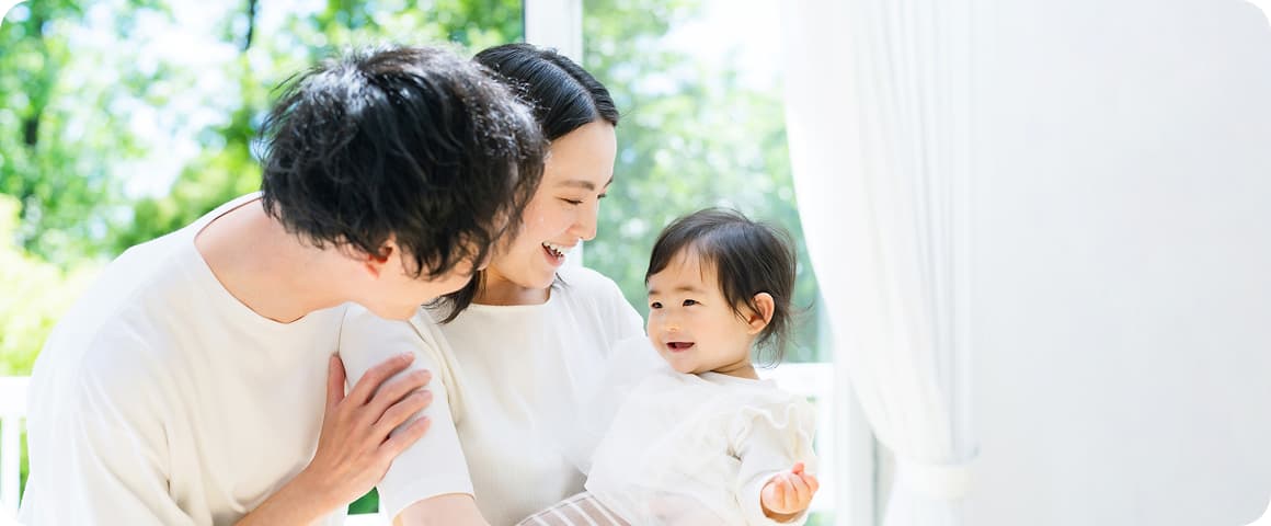 夫婦二人が笑顔でお子さんを抱いています。お子さんも笑顔を見せています。